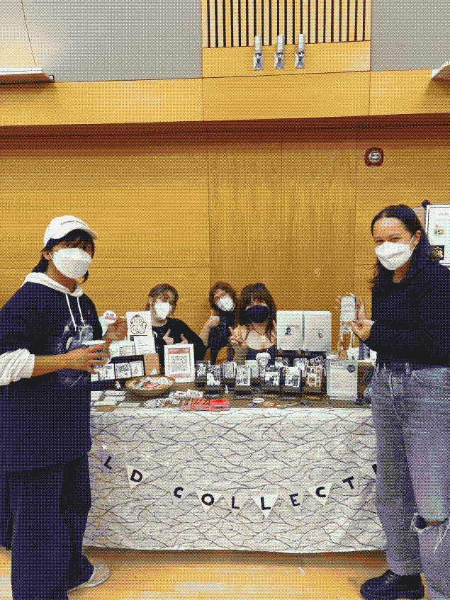 five people gathered around a table set with zines and decorations